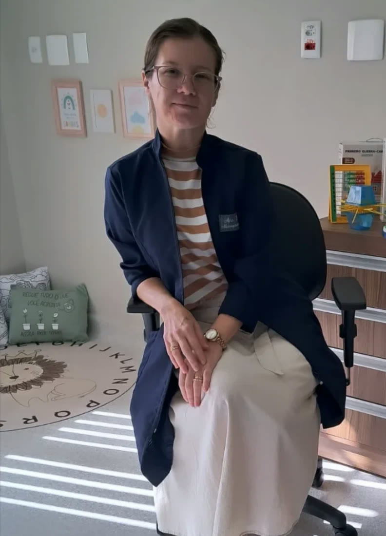 Ana Patrícia no consultório, com jogos e materiais pedagógicos ao lado